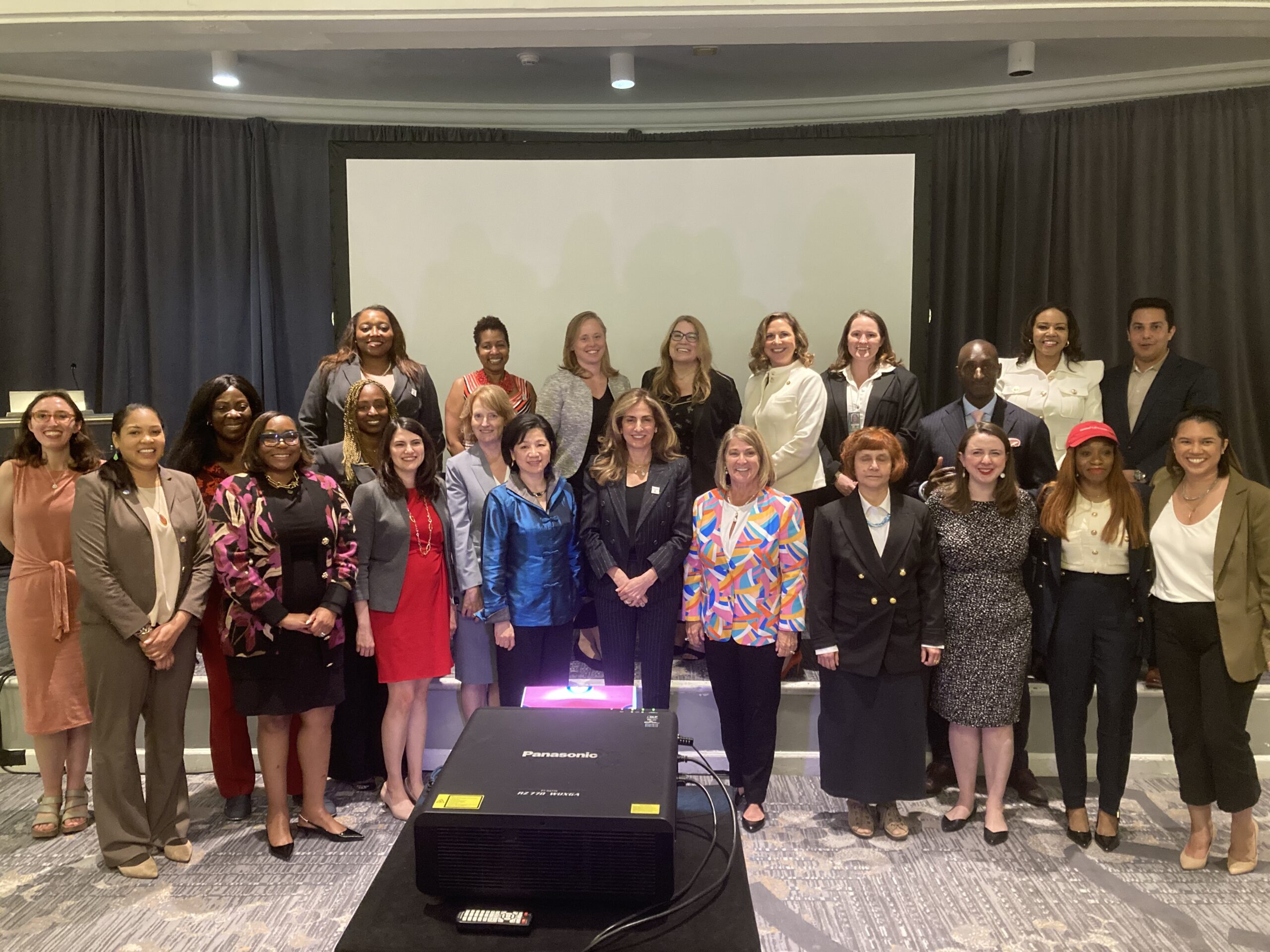 April 30th Access to Opportunity Roundtable participants pose as a group on the stage in the District Ballroom.